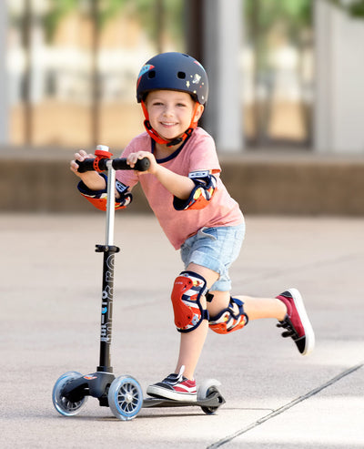 toddler wearing rocket knee and elbow pads while on scooter