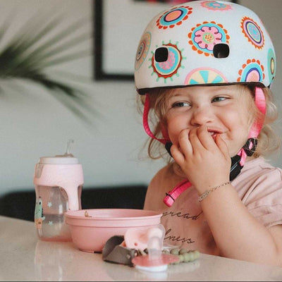 toddler eating her lunch while wearing her scooter bike helmet
