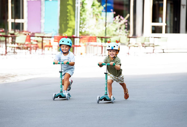 toddlers scooting on the Mini Micro Deluxe Eco scooter deep green