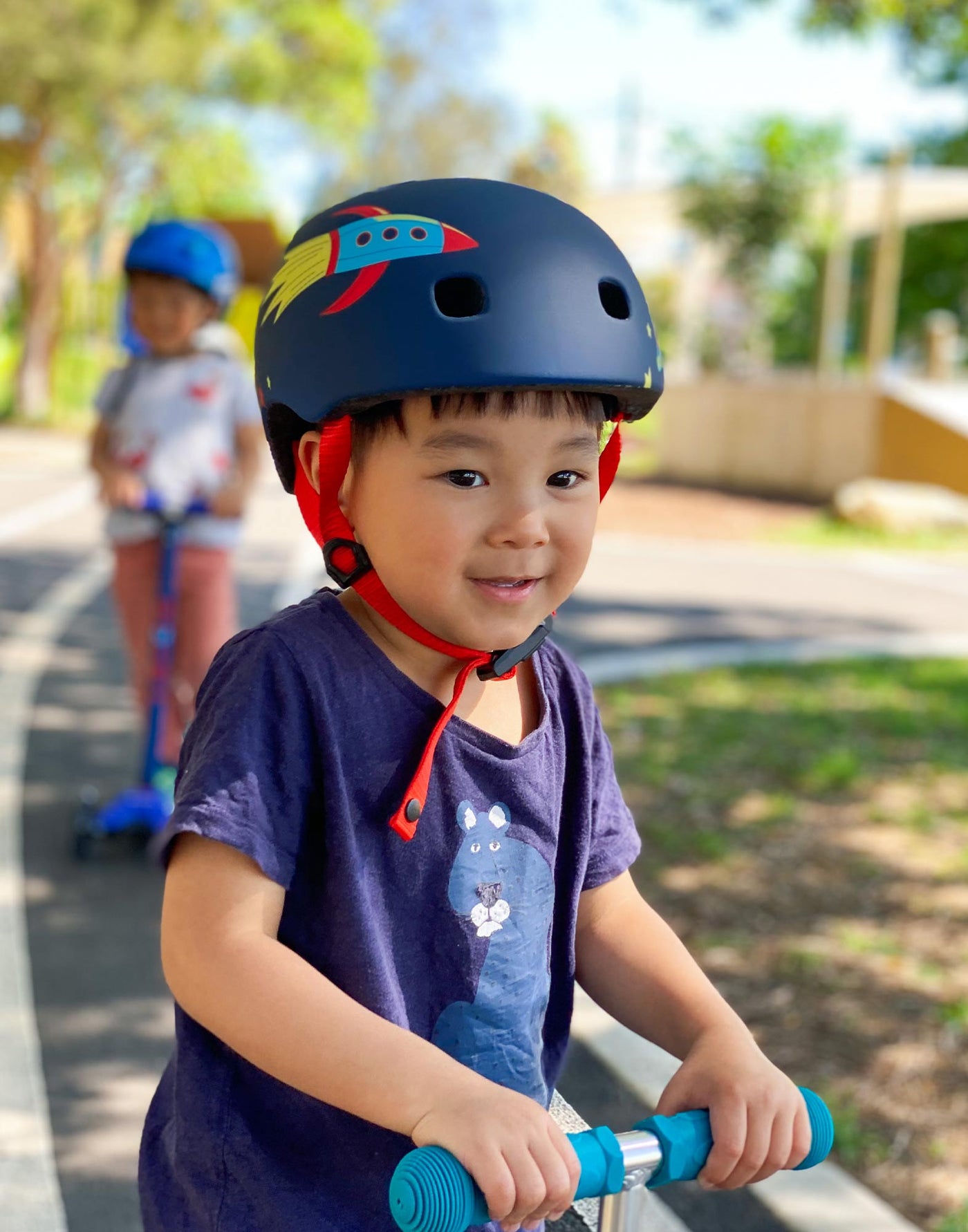 boy wearing a rocket and space themed helmet while on his scooter