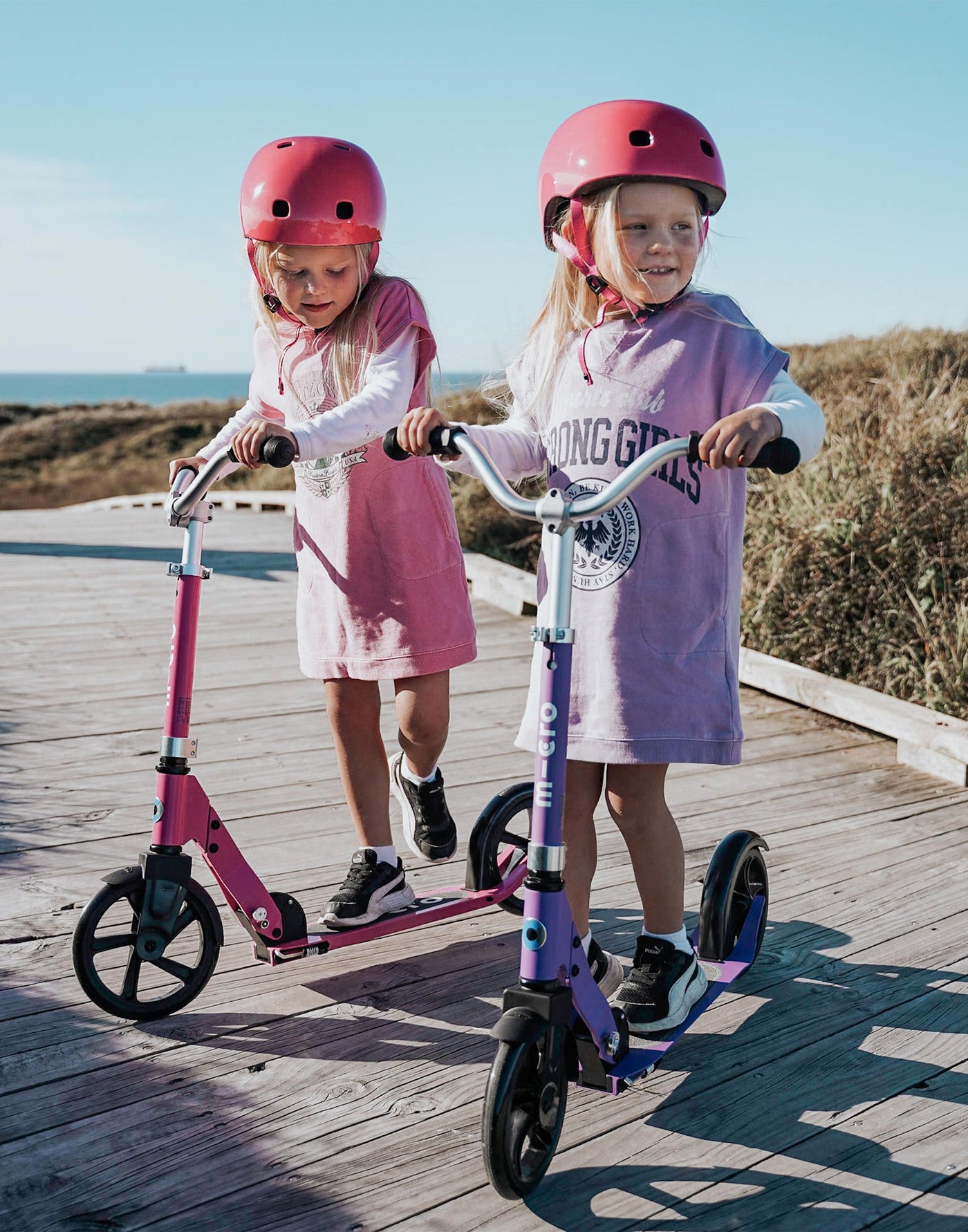 girls riding pink and purple retro kids scooters