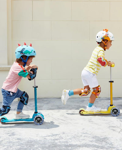 kids having fun racing on their scooters with monster and dinosaur helmets