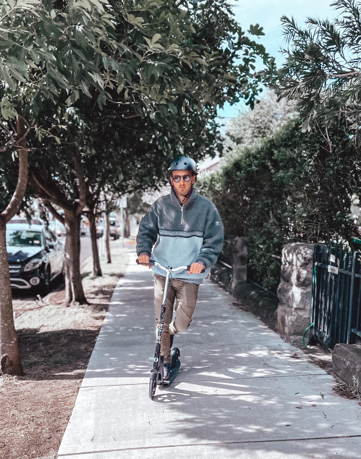 man riding on the footpath on his black downtown commuter scooter