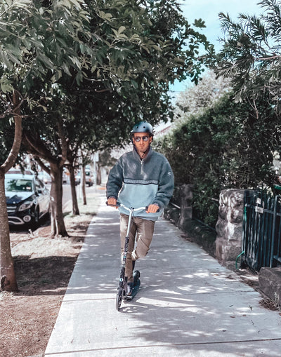 man riding on the footpath on his black downtown commuter scooter