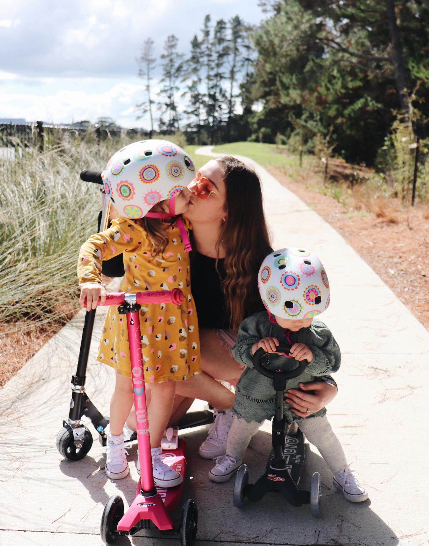 young girls on their scooters with their mums wearing cool pattern helmets