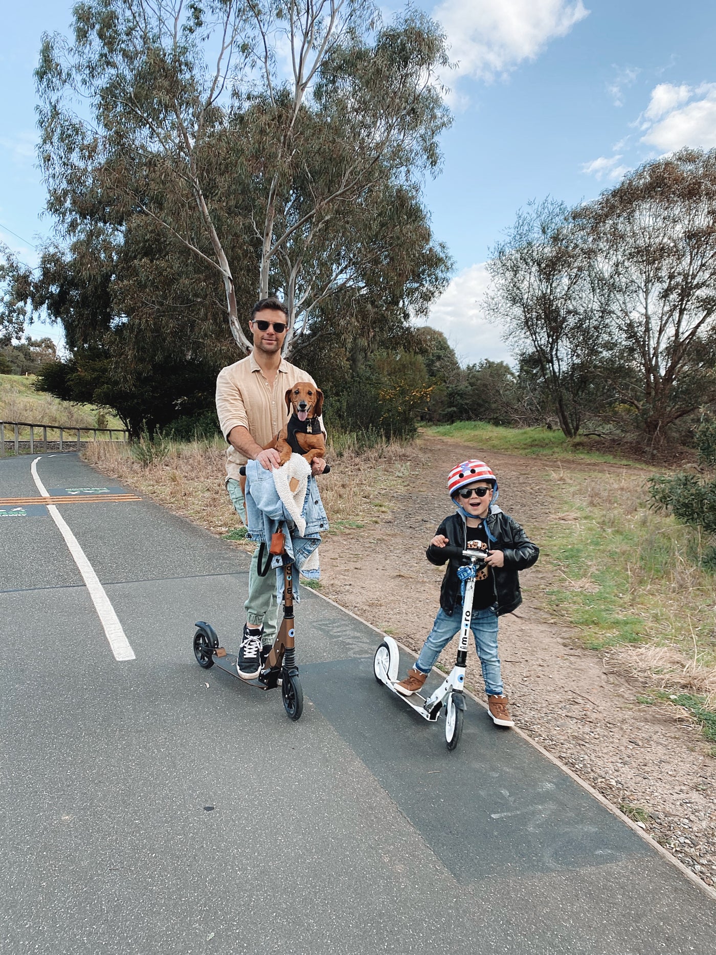 dad riding his bronze suspension adult scooter with toddler and dog