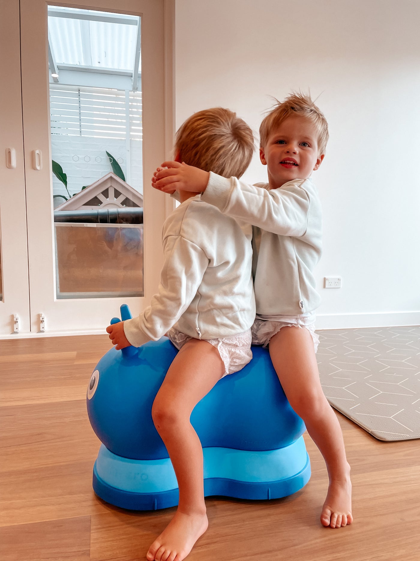 two young boys riding on their blue air hopper