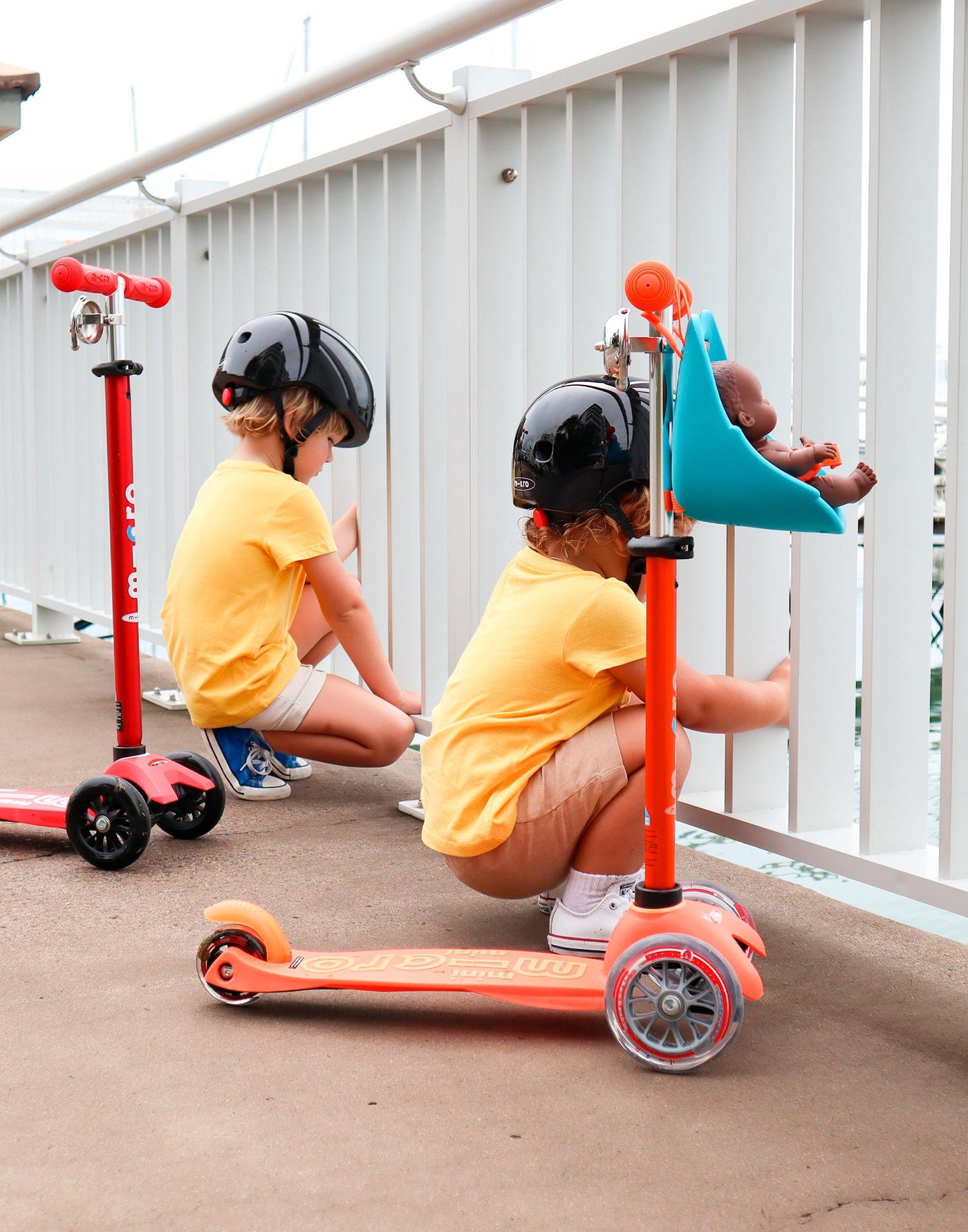 toddlers with their mini deluxe scooters on a bridge