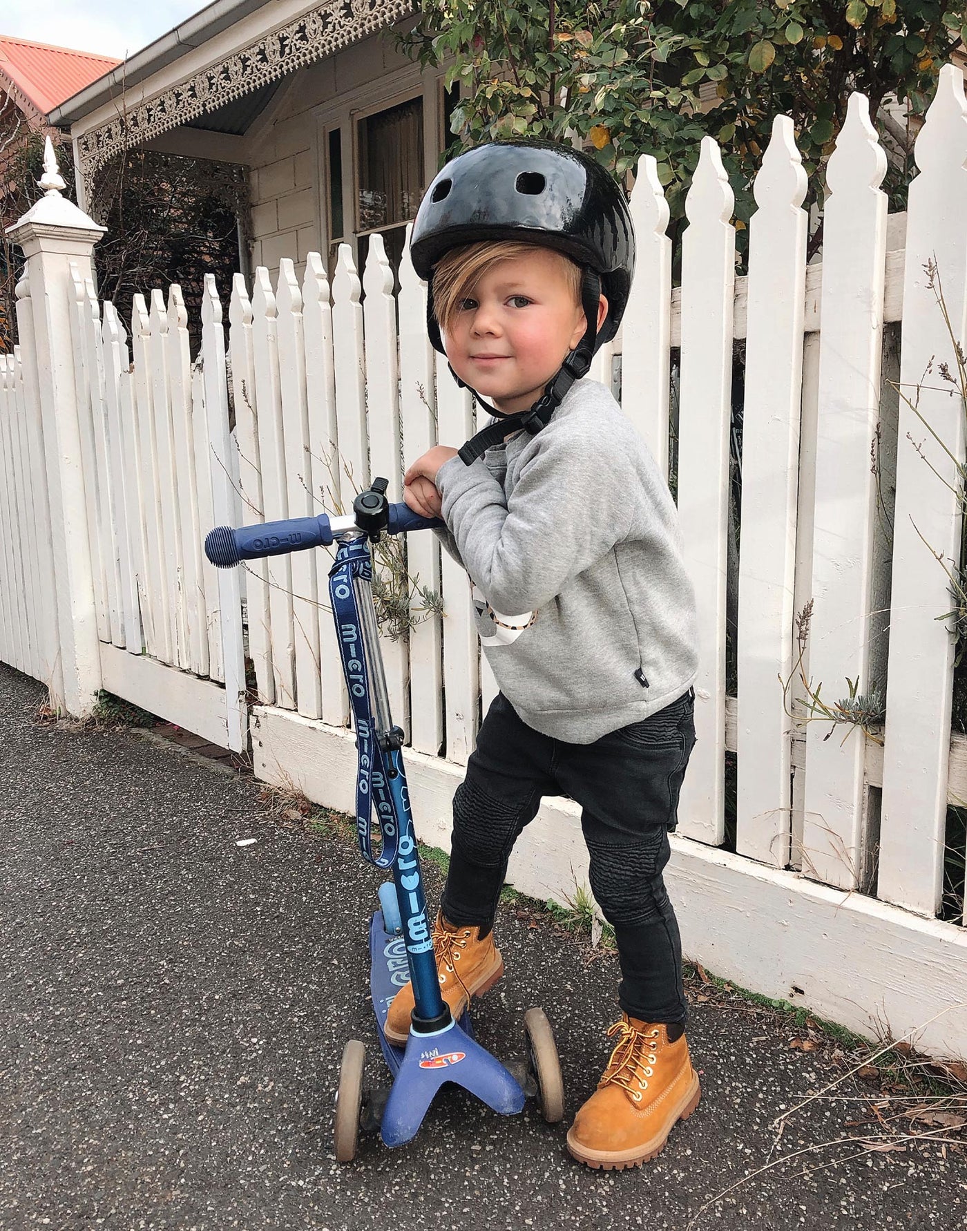 boy riding his blue mini deluxe scooter with carry strap