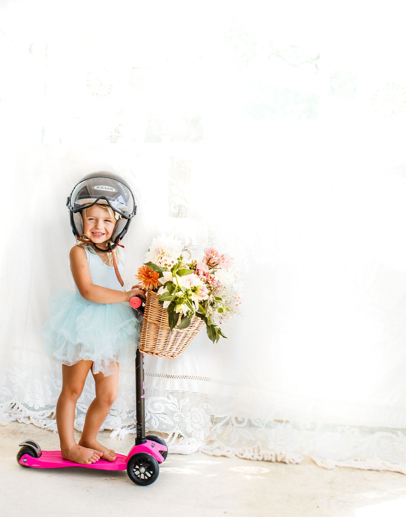 girl riding her pink 3 wheel scooter