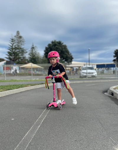 young girl on her pink mini deluxe 3 wheel scooter