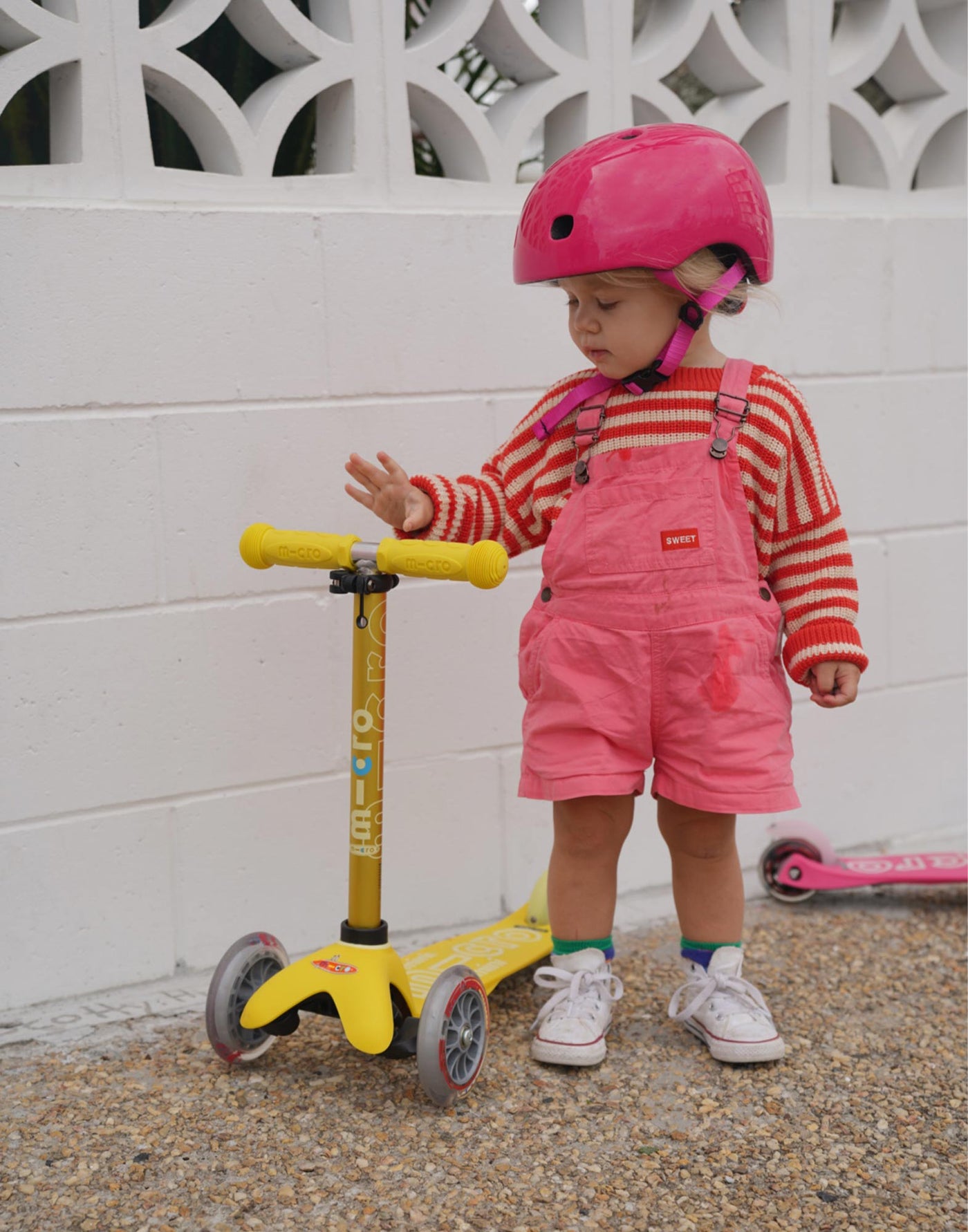 toddler with pink helmet and yellow mini deluxe scooter
