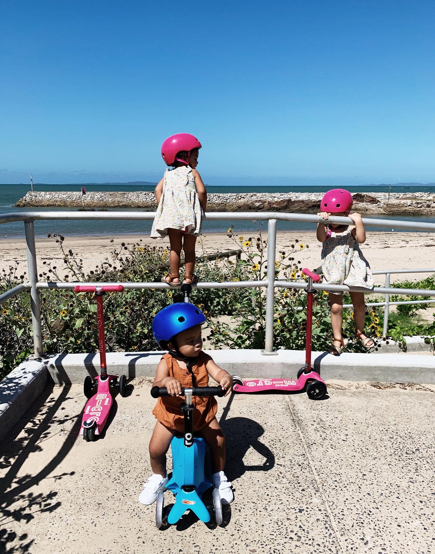 kids wearing their favourite pink and blue helmets at the beach