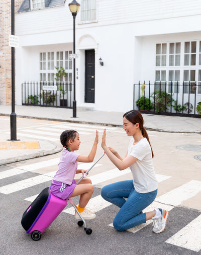 mum and daughter high fiving while riding eazy luggage suitcase