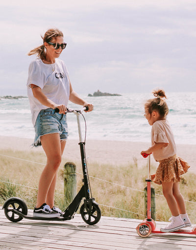 mum on her downtown adult scooter with toddler at the beach