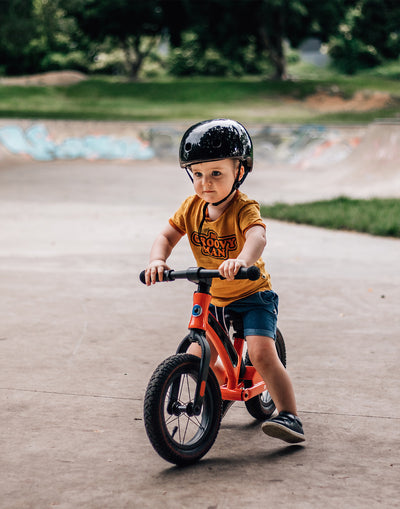 toddler riding his favourite red balance bike